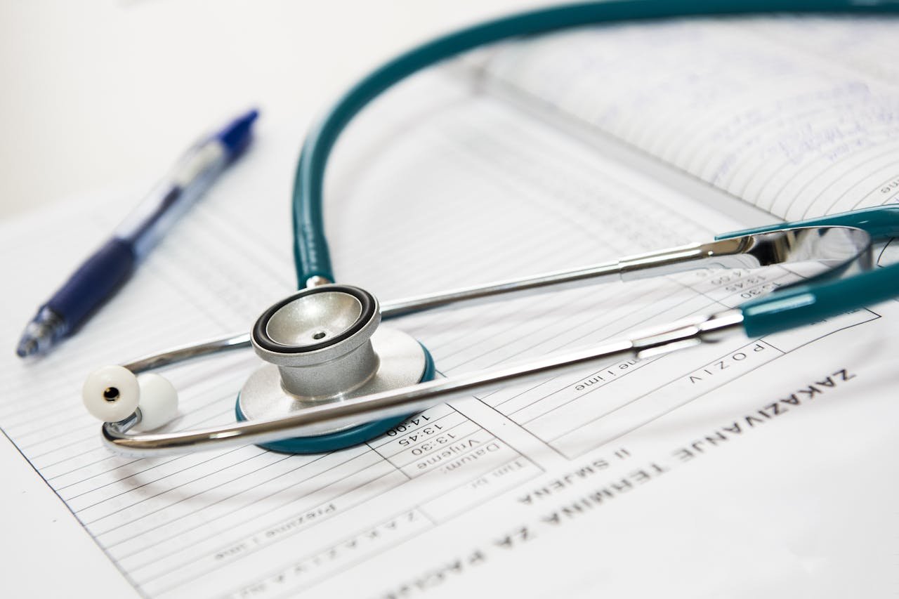 A stethoscope and pen resting on a medical report in a healthcare setting.